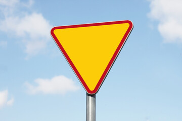 Give way road sign. Traffic safety. Empty copy space isolated on blue sky. Priority lane ahead.