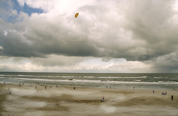 Stormy sky with clouds. Beach scene with flying kite. and miniature view of people on the sands. Thornham Beach Norfolk UK 2003
