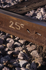 vertical image of railway track section with nails, stones under lying lines, and chalk number markings at woodbridge rail station suffolk uk in 2003. closeup view.