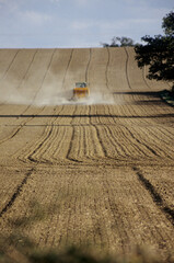 vertical image of tractor with seed drill in agricultural field. drill patterns on top soil. dry dusty soil conditions. sky with clouds. horizon line. Location Keysoe North Bedfordshire UK 1998