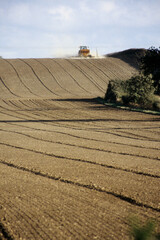 vertical image of tractor with seed drill in agricultural field. drill patterns on top soil. dry dusty soil conditions. sky with clouds. horizon line. Location Keysoe North Bedfordshire UK 1998