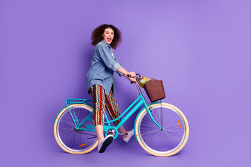 Full body profile photo of cool nice girl drive bike empty space wear denim shirt isolated on violet color background