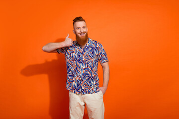 Photo of cool funky guy dressed print shirt showing thumb up empty space isolated orange color background
