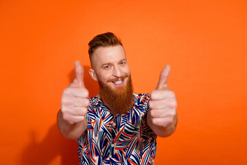 Photo of cheerful excited guy dressed print shirt showing you two thumbs up isolated orange color background