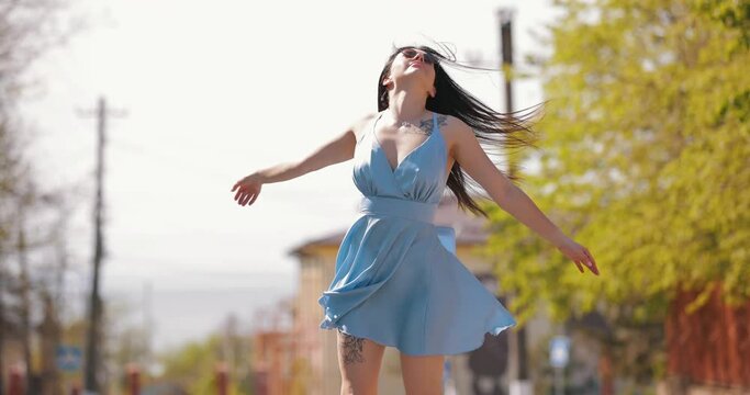 Happy freedom woman in blue dress rotating in the spring city, slow motion