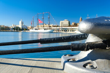 Close-up of metallic bollard with black ropes at Turkish dock under blue sky, with distant bridge...
