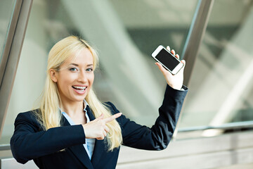 Happy businesswoman pointing with finger at mobile phone - 789259910