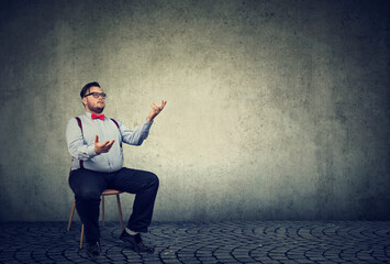 Young businessman sitting on a chair juggling with his hands  - 789259956