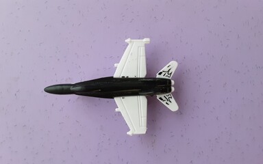  Top view of jet fighter plastic toy airplane on purple surface.