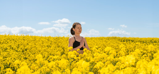 A woman meditating and enjoying the outdoors in a yellow canola flower field