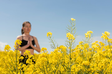 selective focus, Woman meditating in a yellow rapeseed field, springtime. de-stressing from everyday life