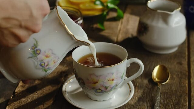 Pouring milk into tea cup. Tea party.