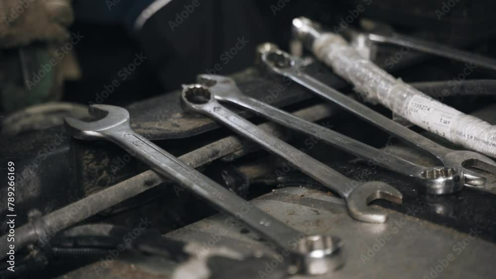 Poster Close-up of the hands of an unrecognizable working man taking a wrench to repair a car. Close-up