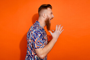 Photo of furious angry guy dressed print shirt screaming empty space isolated orange color background