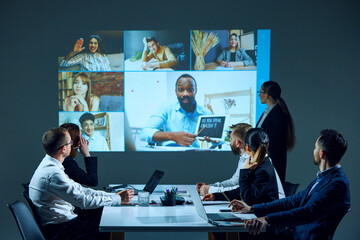 Education courses launching. Workers in office setting engage in virtual meeting, with coworkers...