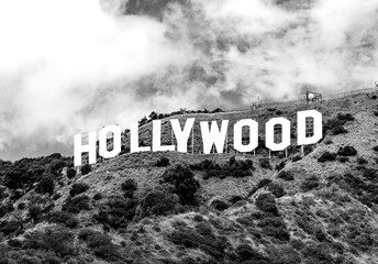 The Hollywood Sign is an American landmark and cultural icon overlooking Los Angeles, California, situated on Mount Lee. Big bright white letters on a hill. Black and white greyscale, vintage.