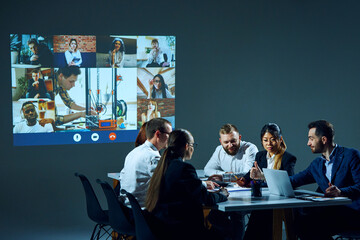 Office employees join a video call from the boardroom, discussing business matters and sharing...