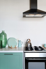 Gas stove, cooker hood and kitchenware in modern kitchen