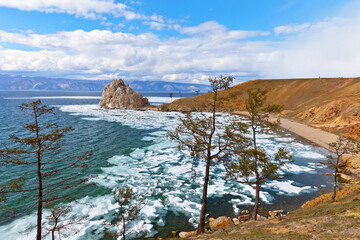 Scenic spring landscape of Baikal Lake in May. View of famous Shamanka rock - natural landmark of Olkhon Island and ice drift in Khuzhir bay on sunny windy day. Beautiful landscape. Spring travels