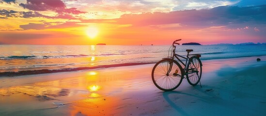 A bicycle is parked on the beach at sunset