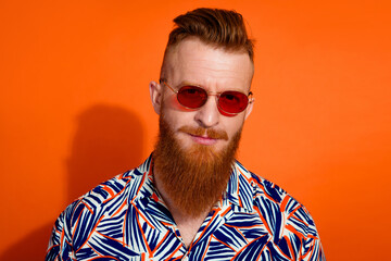 Photo of virile guy with red beard trendy heaicut wear stylish shirt in sunglass look at you isolated on vibrant orange color background