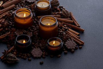 Soy scented candle in a jar. Coffee beans, anise, cinnamon spices. The candles are burning. Dark...