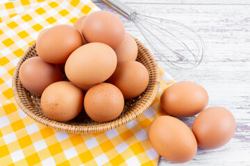 Fresh eggs in a wooden basket on the table.