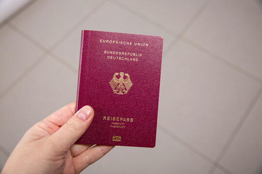 Close up of a female hand holding a German passport, blurry background