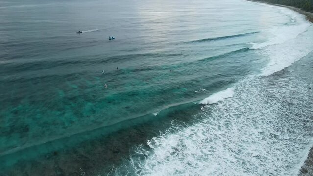 Aerial view of ocean with surfing waves, surfers and boat on Fuvahmulah island