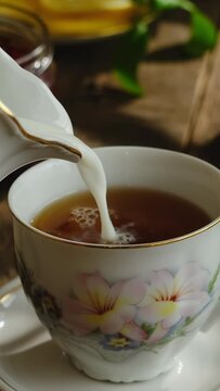 Vertical video. Pouring milk into tea cup. Tea party.