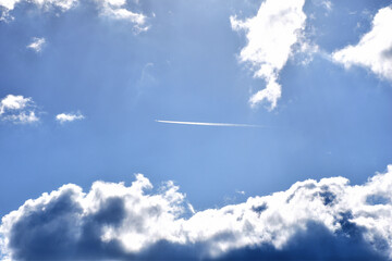青空に浮かぶ雲の間を飛んで行く飛行機