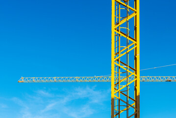 Two yellow construction cranes forming a cross as abstract background