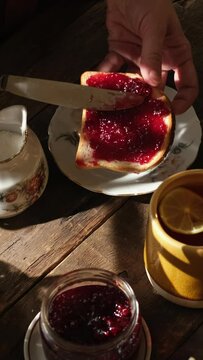 Vertical video. Rustic breakfast. Female hands preparing sandwich with berry jam