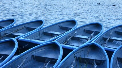 blue plastic canoeing. Many sightseeing blue boats on the lake. renting row boat. Close up blue...