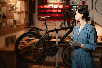 Young repair woman in bicycle garage for working, cycling workshop and startup. Confident bike...