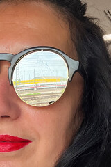 Woman in glasses with railway reflection. Concept of travelling