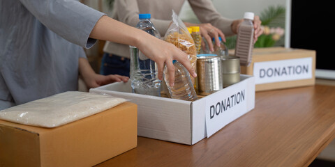 Volunteer preparing free foodstuff rations for poor people. Charity two woman of the community work...