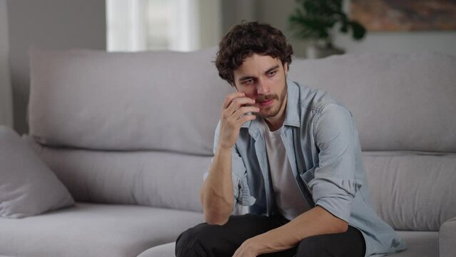 Caucasian young man upset head in hands think concern of job loss being fired sit at home sofa. Cancer patient worry fear pain in hard time crisis bad news. Lonely student pensive tired, sad regret.
