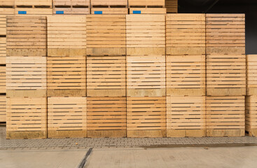 Many large wooden boxes for transporting potatoes or apples are stacked one on top of the other in...