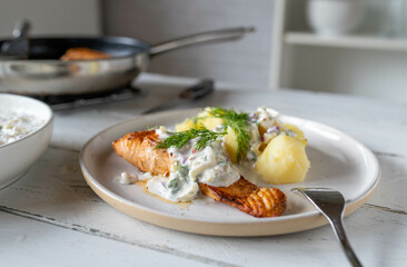 Pan fried salmon fillet with light yogurt apple dill sauce and boiled potatoes on a plate