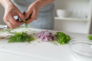 Woman preparing fresh herbs and onions on a cutting board
