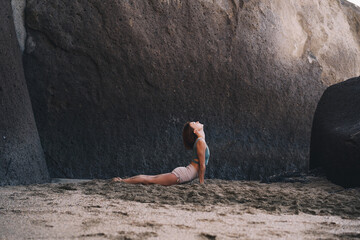 Woman is practicing yoga on the beach. - 789344715