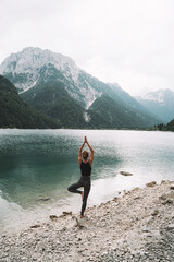 Young woman is practicing yoga at mountain lake. - 789344917
