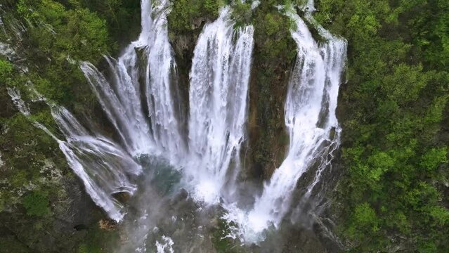 Amazing aerial video of Plitvice national park with lakes and picturesque waterfalls in a green spring forest, Croatia. Drone flight around The Great waterfall.
