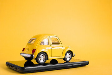 Urban taxi mobile online application concept. Toy yellow taxi car model. Hand holding smart phone...