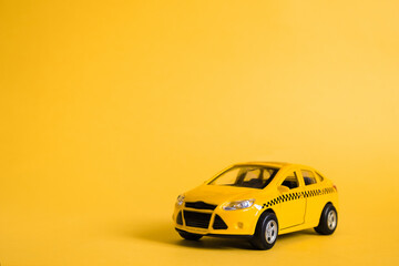 Urban taxi and delivery service concept. Toy yellow taxi car model. Copy space for text, banner. Online mobile application order taxi service.