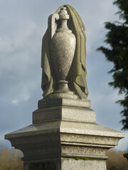 A draped urn is a popular a popular symbol on a gravestone and the fabric represents the veil that separates the living from the dead