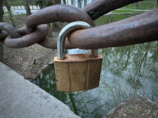 The lock is attached to a rusty chain. A small padlock is attached to the chain. Concept: love is eternal, we are inseparable together.