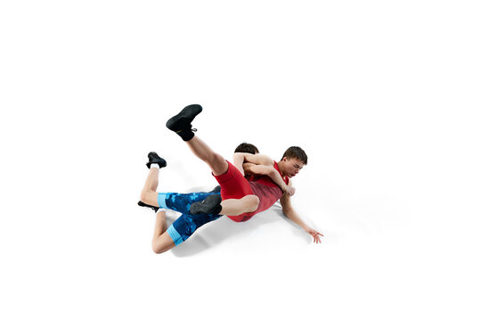 Young men, athletes compete fiercely in wrestling match, displaying determination and skills isolated on white background. Concept of combat sport, martial arts, competition, tournament, athleticism