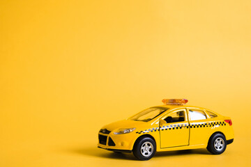 Urban taxi and delivery service concept. Toy yellow taxi car model. Copy space for text, banner. Online mobile application order taxi service.